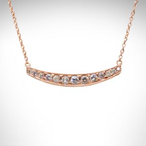 Rose gold bar necklace with slight curve and pave set diamonds with millgrain edge and cable chain.